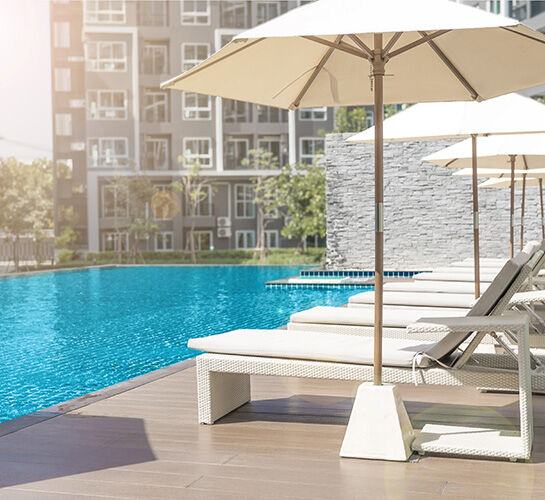 sunbeds and umbrella in front of apartment pool